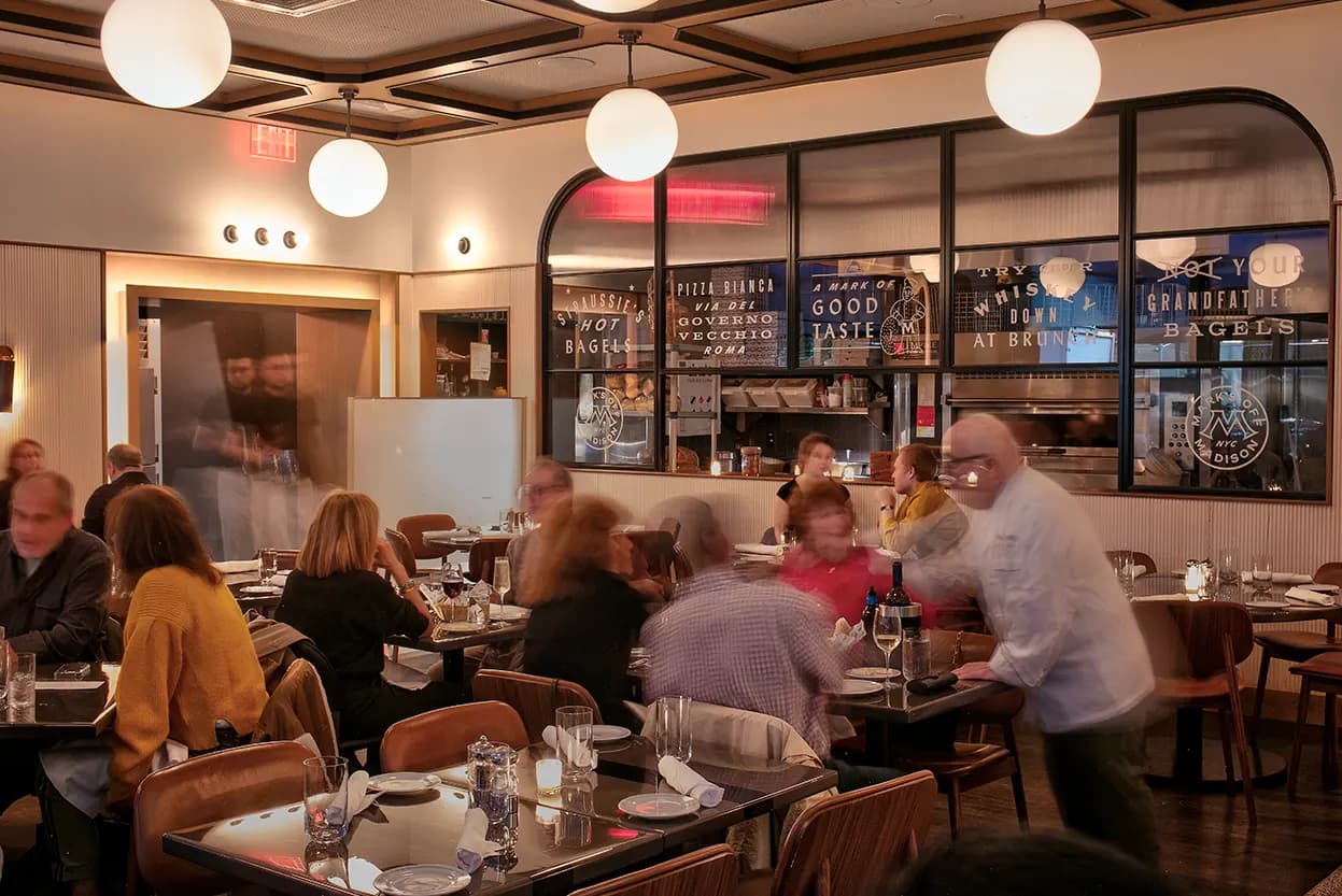 A full dining room at dinner under globe pendant lights