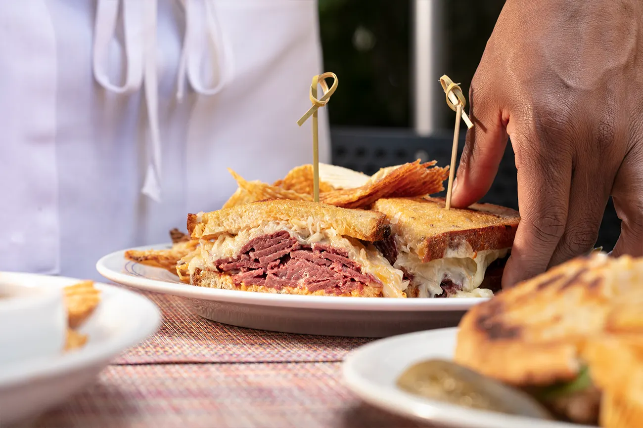 A pastrami Reuben on rye being lifted from the plate