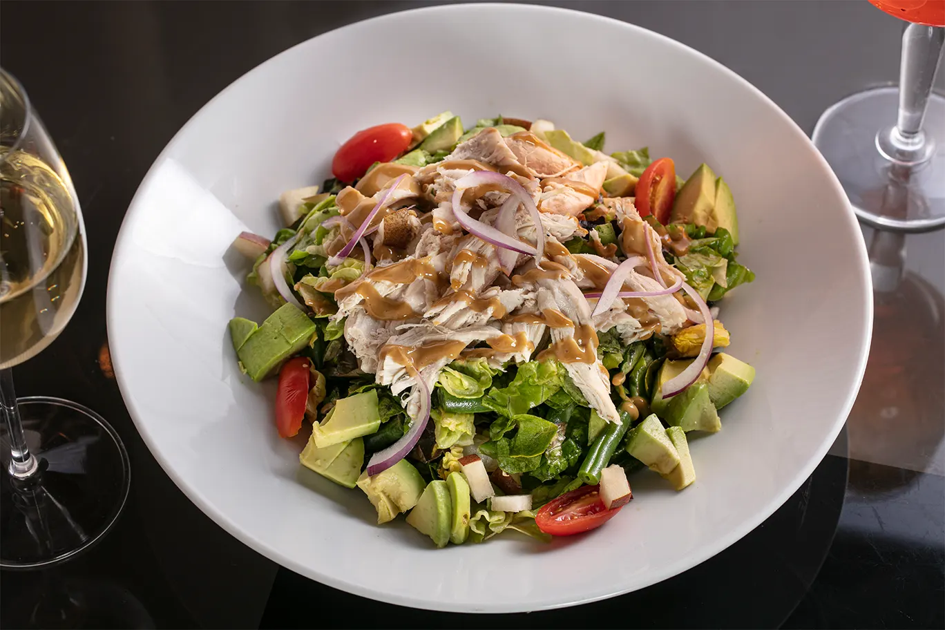 An entrée salad of roasted chicken, avocado, tomato and greens